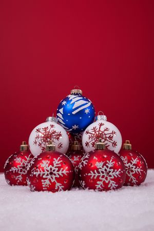 christmas colorful balls over the snow with a red background (selective focus)の写真素材