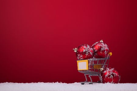 christmas balls in a shopping cart over a red backgroundの写真素材