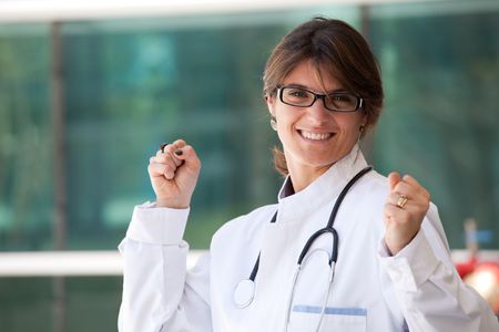 Friendly female doctor smiling to you next to a clinicの写真素材