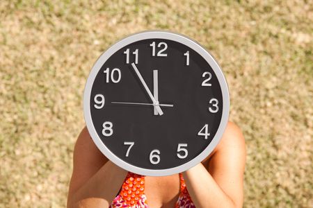 hands holding a clock in front of the faceの写真素材