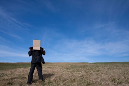 businessman with an box on his head at the fieldの写真素材