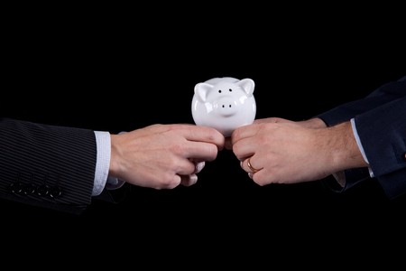 Two businessman competing for money, pushing a piggy bank (isolated on black)の写真素材