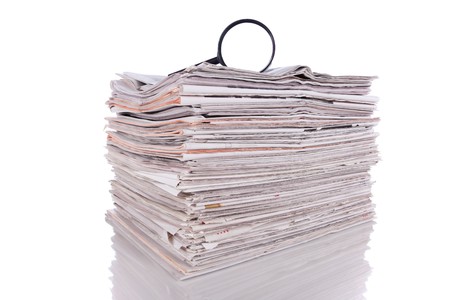 Magnify glass over a stack of newspaper to find fresh information (isolated on white)の写真素材