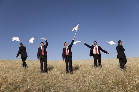 Group of businessman in the field raise the white flagの写真素材