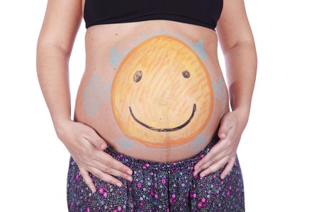 Pregnant woman with a painted belly of a happy and smiling little devilの写真素材