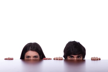 two business person hiding and peeking behind the office deskの写真素材