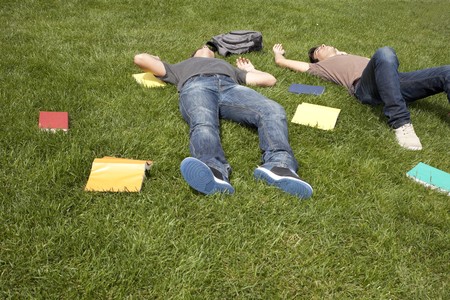 two young student lying down at the school grass after long hours of studyの写真素材