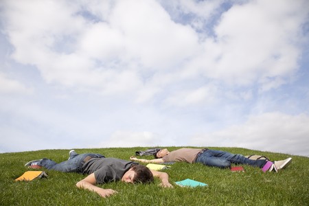 two young student lying down at the school grass after long hours of studyの写真素材
