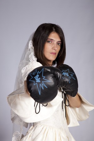 Crazy beautiful bride with boxing gloves (grey background)の写真素材
