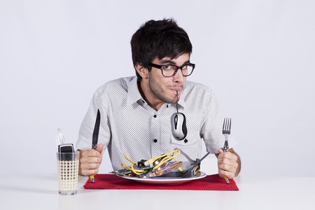 Crazy young man eating technology at his dinner plateの写真素材