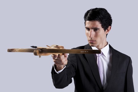 Modern businessman aiming with a crossbow (isolated on gray)の写真素材