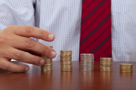 businessman hand over money piles of coinsの写真素材