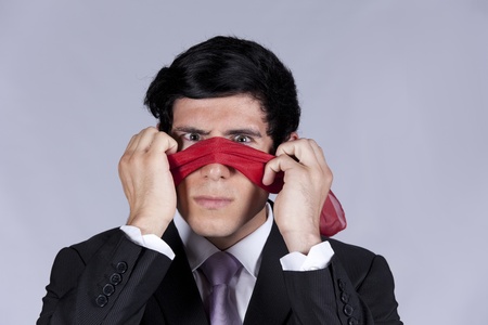 Lost businessman peeking behind a blindfoldの写真素材