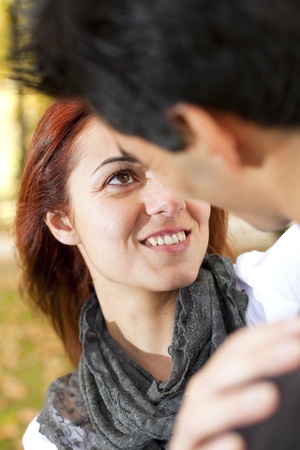 Love and affection between a young couple at the park in autumn season (selective focus with shallow DOF)の写真素材
