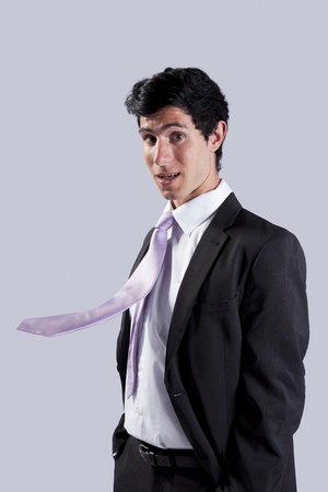 Businessman surprised with his flying necktie (isolated on gray)の写真素材