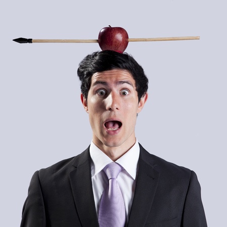 Scared businessman with a apple and arrow over his headの写真素材