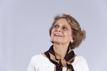 Beautiful senior woman looking up (isolated on gray)