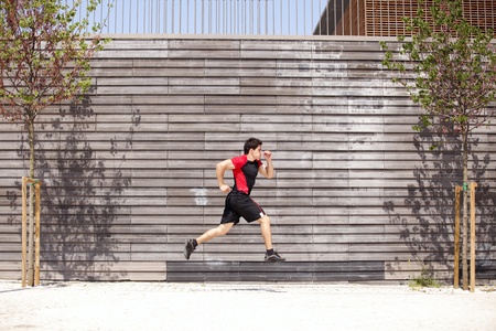 Men athlete running next to some city wallの写真素材