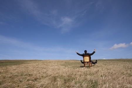 businessman sitting in a chair in outdoor looking to the fieldの写真素材