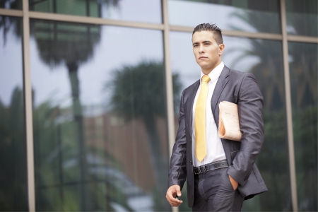 Businessman walking with his newspaper next to his office buildingの写真素材
