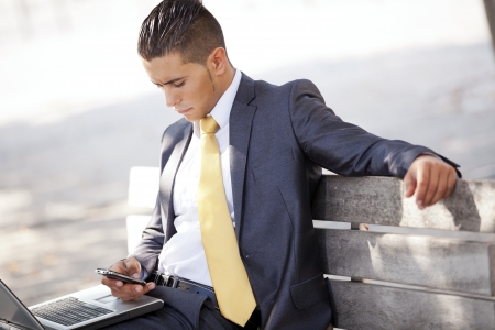 Businessman working sited in a bench at the city parkの写真素材
