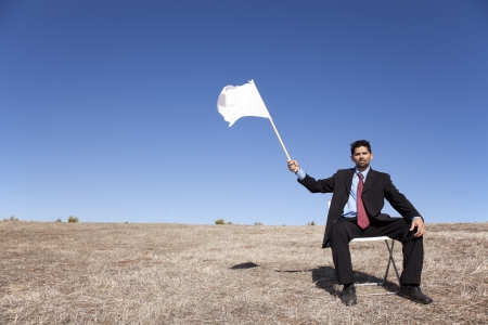 businessman asking for surrendering holding a white flagの写真素材