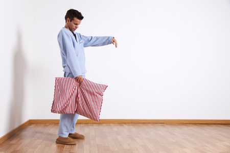 Young man sleepwalking at his home dress with nightclothes (isolated on white)の写真素材