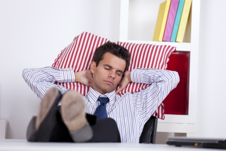 Businessman sleeping at his office with his shoes on the tableの写真素材