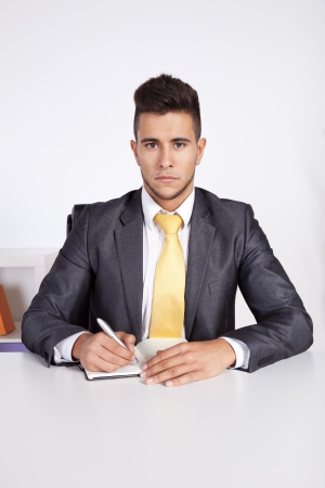 Businessman at his office taking some notes in his agendaの写真素材