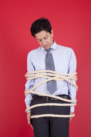 Businessman tied up with a rope struggle to get freeの写真素材
