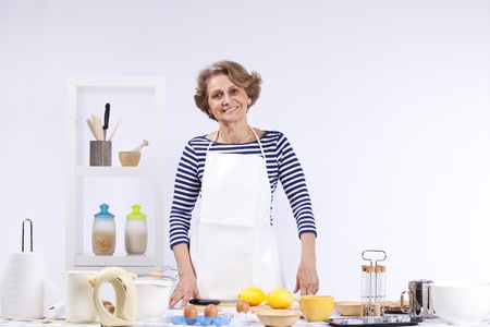 Beautiful and happy senior woman cooking at her kitchen