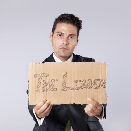 young businessman holding a piece of cardboard saying that he is the leaderの写真素材