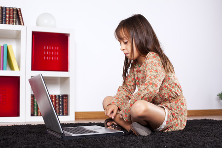 Little girl at her home using a laptop computerの写真素材