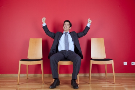 One successful businessman between two empty chairsの写真素材