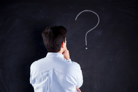 Businessman looking at a chalkboard with a question markの写真素材