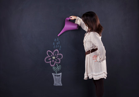 Woman watering a plant draw in a chalkboardの写真素材