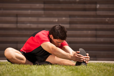 Athlete male at the city park warming and stretchingの写真素材