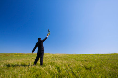 Businessman working with a laptop outdoors in a fieldの写真素材