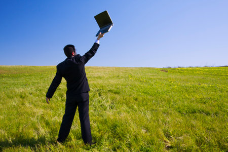 Businessman working with a laptop outdoors in a fieldの写真素材
