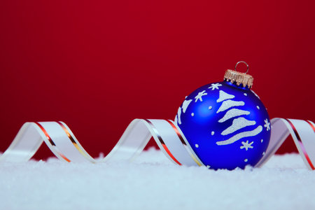 Christmas colorful balls over the snow with a red background (selective focus)の写真素材