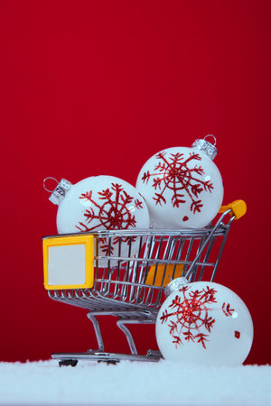 Christmas balls in a shopping cart over a red backgroundの写真素材