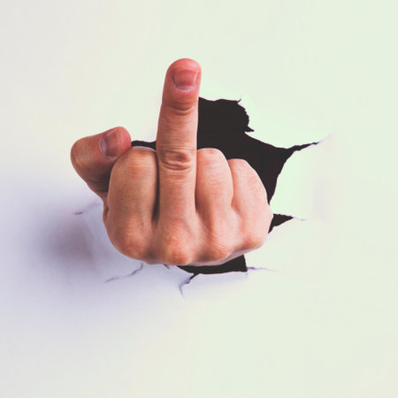 Hand through a paper with an offensive gestureの写真素材