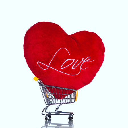 Red heart pillow in a shopping cart (isolated on white)の写真素材