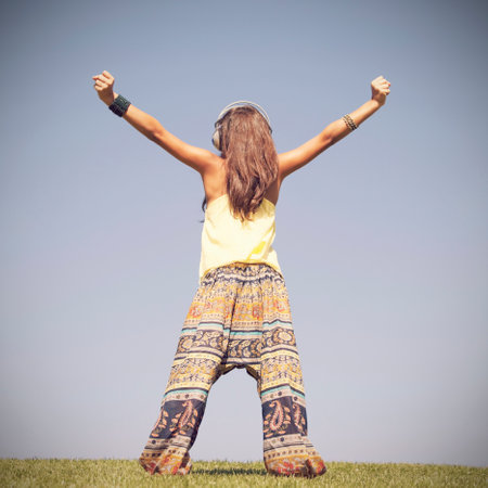 young female child listening to music in the fieldの写真素材