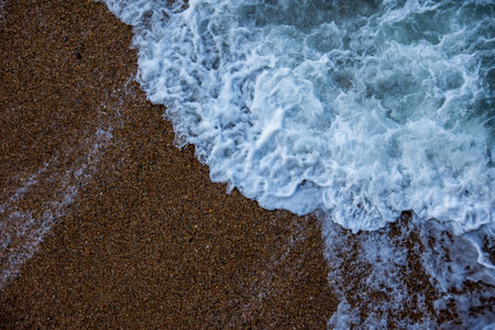 Ocean wave hitting the sand. View from above. Close-up shot for texture