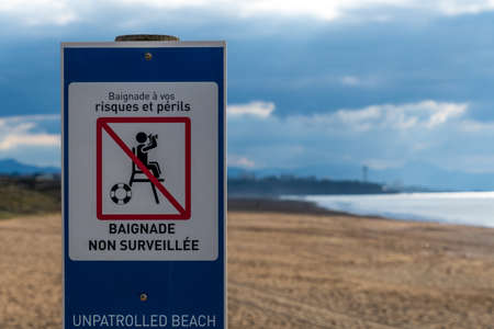 Sign written in French and English indicating an unpatrolled beach. Atlantic coast, Anglet, Franceの写真素材