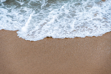 Ocean wave coming on the sand. Close-up view from above. Texture for background. Copy space for textの写真素材