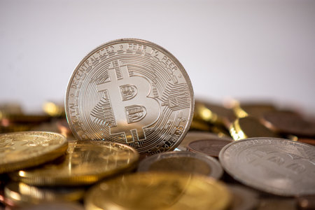 A silver bitcoin standing among many blurred coins.の写真素材