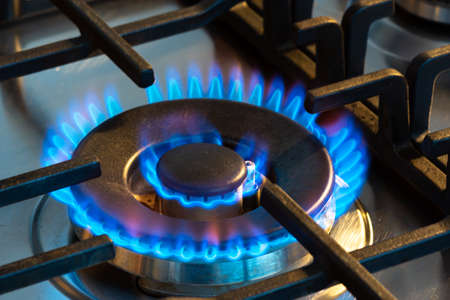 Gas burning with blue flames on the burner of a gas stove. Concept of carbon footprint and price of natural gas on the marketの写真素材