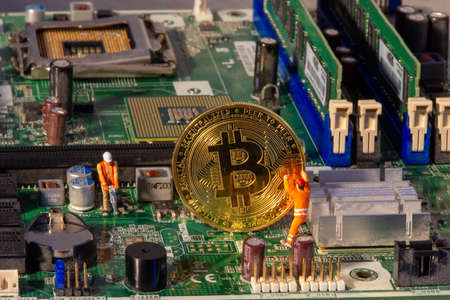 Bitcoin mining inside a computer. Two small Bitcoin miners figurines extracting valuable...